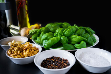 Ingredients for pesto on black ground. Homemade basil pesto sauce and ingredients on dark  background. Front view