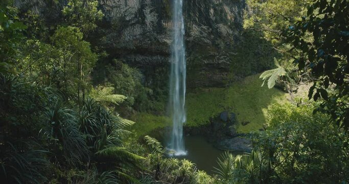 Very soft and thin waterfall falling down a steep and high mountain in the forest / jungle - Bridal Falls - New Zealand