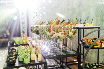 Large table with snacks of different types at a party with creative disco lighting.