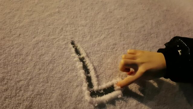 Closeup of writing the word LOVE with a finger on fresh winter snow at night