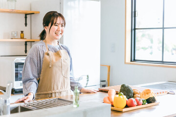 キッチンに立つエプロン姿の日本人女性
