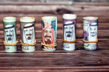 Saudi Arabia money roll riyals banknotes isolated on wooden background, Saudi riyals cash money...