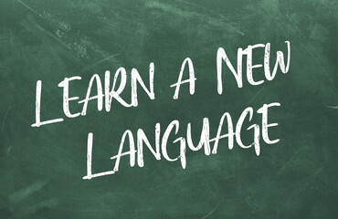 Obraz premium Learn a New Language written on the green chalkboard