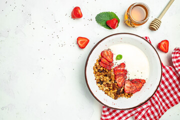 Bowl of homemade granola with fresh strawberry, chia seeds and honey on a light background. Delicious breakfast or snack. banner, menu, recipe place for text, top view