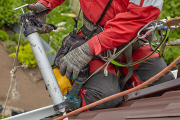 A specialist is repairing the roof. Rope access