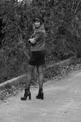 Slim woman in leather jacket standing on a road in black and white