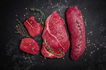 Beef tenderloin fillet with rosemary and spices on a dark background. Preparing fresh beef steak ready to cook, Long banner format. top view