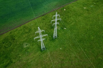 Drone shot over high voltage electric power transmission towers with power lines running across...
