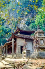 Eingescanntes Diapositiv einer historischen Farbaufnahme einer buddhistischen Tempelanlage am Fusse eines Felsens in Nordvietnam