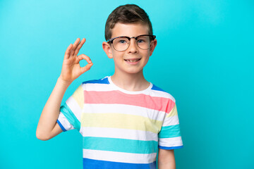 Little boy isolated on blue background With glasses and doing OK sign