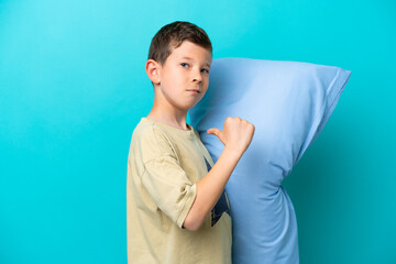 Little boy in pajamas isolated on blue background proud and self-satisfied