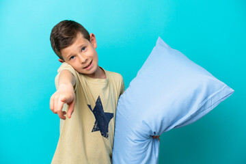 Little boy in pajamas isolated on blue background pointing front with happy expression