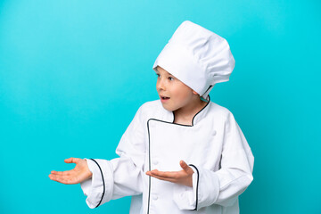 Little chef boy isolated on blue background with surprise expression while looking side