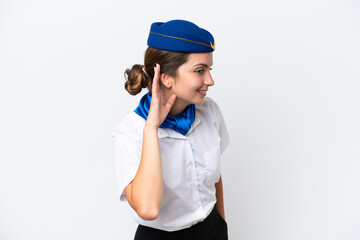 Airplane stewardess caucasian woman isolated on white background listening to something by putting hand on the ear