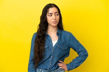 Young caucasian woman isolated on yellow background having doubts while looking side