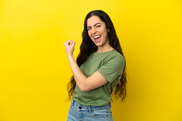 Young caucasian woman isolated on yellow background celebrating a victory