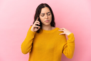 Young caucasian woman using mobile phone isolated on pink background suffering from pain in shoulder for having made an effort