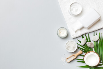 Coconut with jars of coconut oil and cosmetic cream on colored background. Top view. Free space for your text. Natural spa coconut cosmetics and organic treatment concept Coconut Spa composition