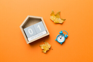 Wooden calendar block with date 1 october with falling autumn leaves background
