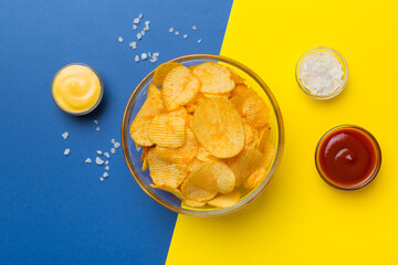 Top view chips with sause in bowl on colored background, top view with copy space
