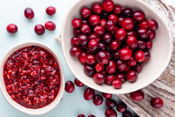 Cranberries in white bowl on pastel background.