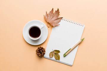 Obraz na płótnie Canvas Autumn composition: fallen leaves and notebook mock up on colored background. Top view. Flat lay with copy space