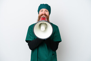 Surgeon redhead man in green uniform isolated on white background shouting through a megaphone