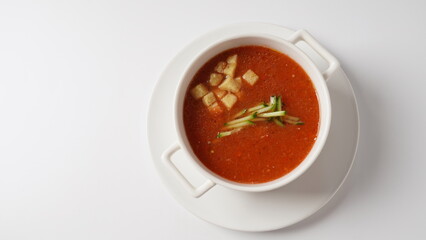 Bowl with  homemade Gazpacho tomato soup, with croutons and sliced cucumber. Spanish cold tomato based soup