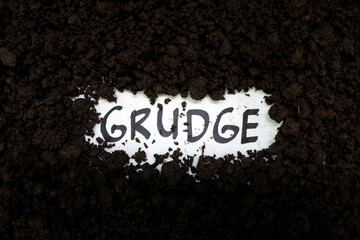 Bury grudge and stop holding concept. Grudge text word on soil backdrop.
