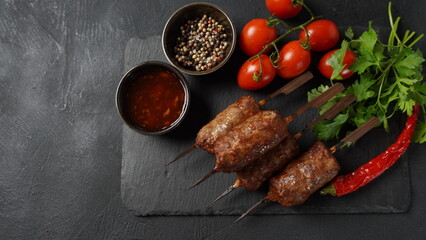 Shish kebab is a popular meal of skewered and grilled cubes of meat. Roasted Beef Kebab on a wooden skewer with spices, herbs, and tomatoes