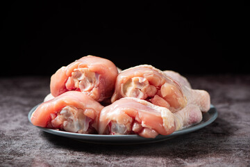 Raw chicken drumsticks in plate on table