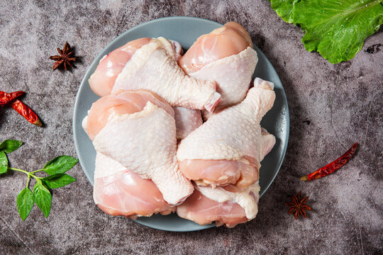 Raw Chicken Drumsticks In Plate With Seasonings On Table