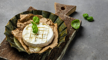 Oven baked camembert cheese with basil leaves on baking paper. Homemade grilled brie on rustic table. banner, menu, recipe place for text, top view