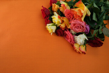 bouquet of yellow, red, pink roses with a copy space for the designer, flowers for professional holiday on an orange background, concept of mother's, Valentine's day, birthday, selective focus