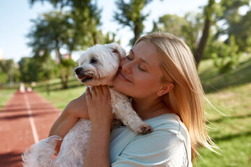 Girl with closed eyes hugging furry Maltese dog