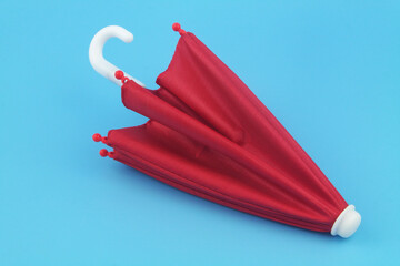 Small red umbrella on blue background.