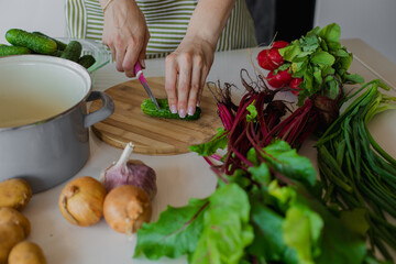 Cropped woman hands chop fresh vegetable on wooden board in kitchen. Raw food recipe, homemade dish for health, immunity