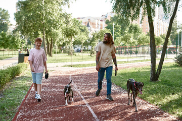 Father and son walking with dogs on running track