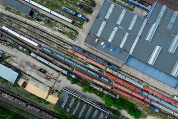 Aerial top down view of an industrial railroad yard with rows of train cars on railroad tracks
