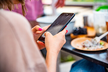 woman hand holding and using smartphone in outdoor cafe