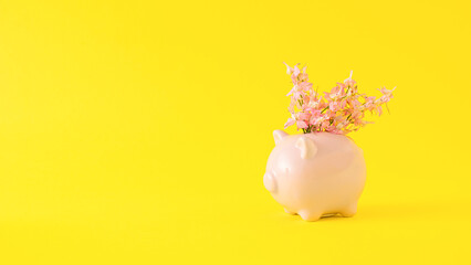 Creative arrangement made of pink piggy bank and flowers. Minimal enrichment and savings concept. Summer, spring and blooming inspiration.