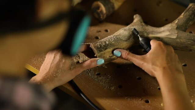 Female using power wood working tools graver, carving while crafting, Creating craft handmade souvenirs, woman in workshop.