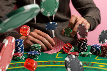 Gambler man hands pushing large stack of colored poker chips across gaming table for betting