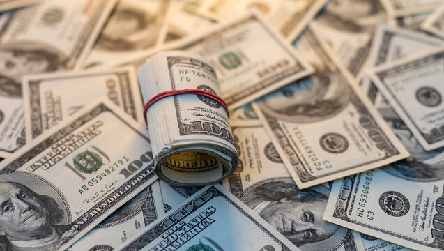 A roll of money tightened by an elastic band close-up macro shot. Usd money wad, bundle of usa cash. Several American dollar bills rolled and tied up. George Washington portreture