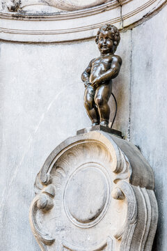 Brussels, Belgium - April 21, 2019: Manneken Pis is a historic fountain in the old town, made of a bronze statue by Jerome Duquesnoy the Elder, depicting a naked little boy standing and urinating.