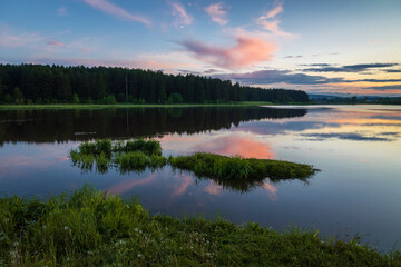 A beautiful sunset landscape of the countryside with a lake and reflection in the water.