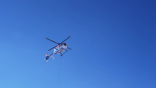 Rescue helicopter landing on the slopes helping skier in a ski park. Air ambulance in Alps. Rescue transportation.