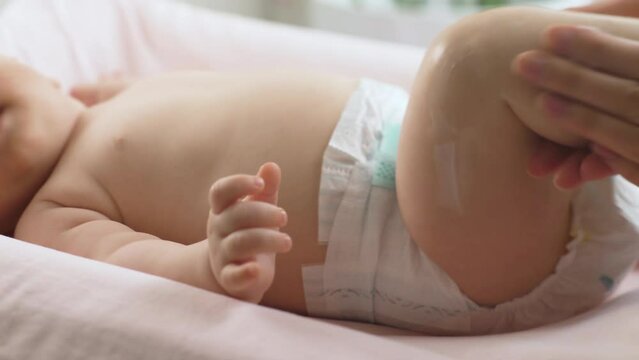Mother applying moisturizing baby cream against dry skin. Concept of hygiene, baby care and healthcare.