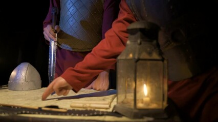 Medieval concept.
Historical war analysis. Historical documentary. Ancient candle lamp lantern. Sword, armor, medieval outfit.
