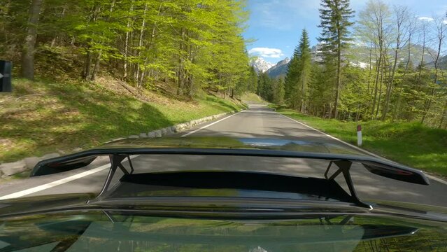GIAU PASS, DOLOMITES, ITALY, MAY 2022: Picturesque drive with a view back towards car spoiler and mountain landscape. Exploring beautiful alpine land while driving on the winding asphalt mountain road